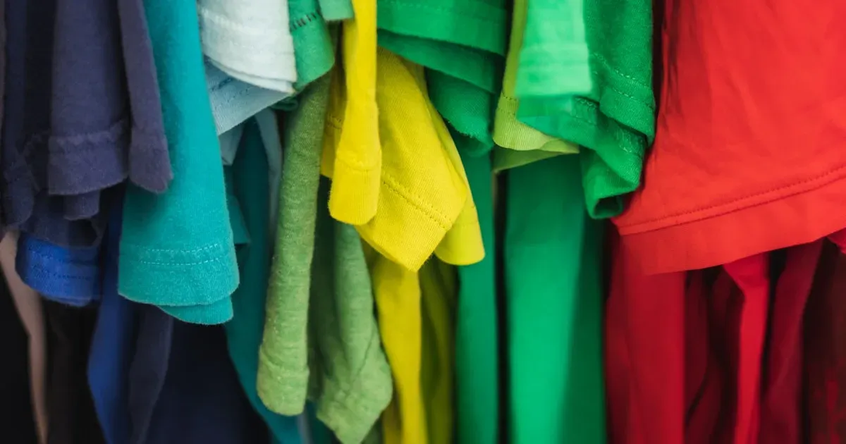 Camisetas penduradas em várias cores em arara de loja