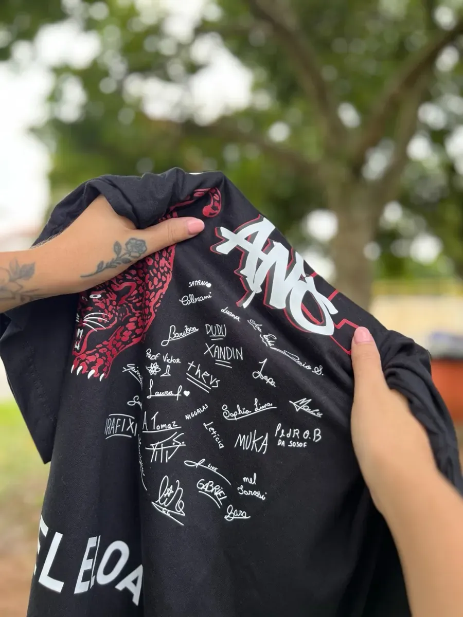 Camiseta preta com as assinaturas da turma estampadas