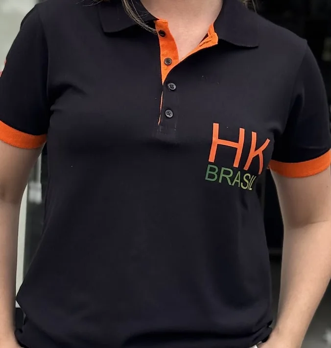 Bordado HK Brasil em camisa polo preta com placket e punhos em laranja
